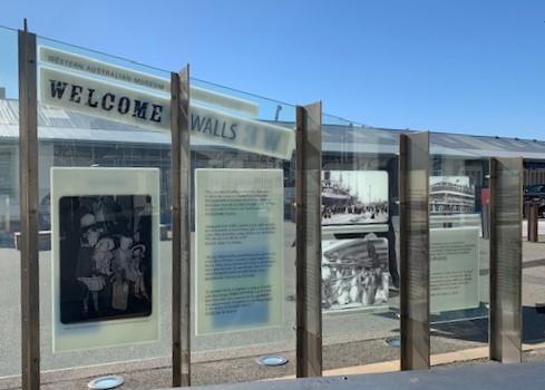 Glass panels in a steel frame-work that feature text and images introducing the Welcome Walls.