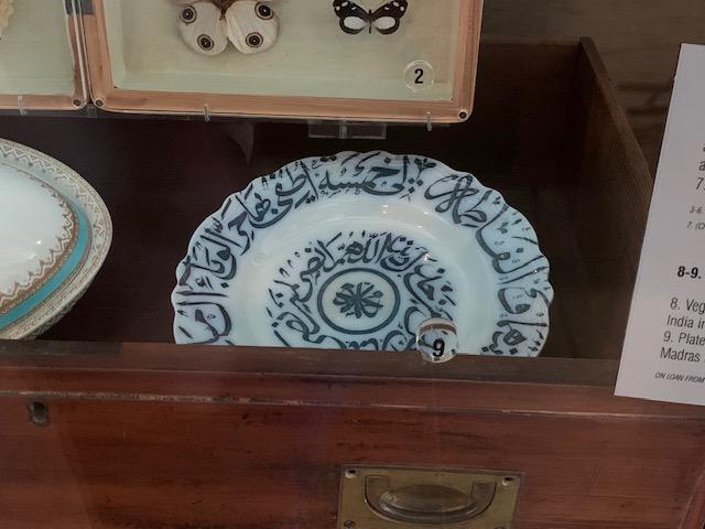 A white ceramic plate with an intricate blue design sits inside a timber drawer with brass handle.