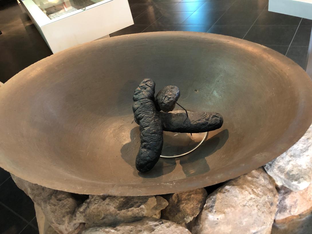 A large metal pan resting on stones. There are cooked sea slugs in the centre.