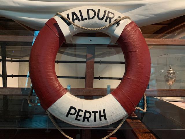 Circular red and white life preserver with the names Valdura and Perth written on it.