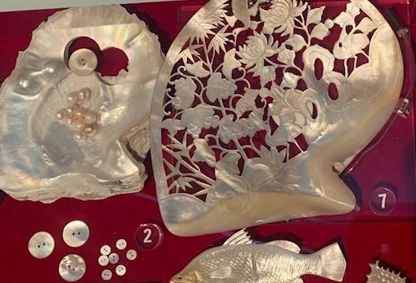 Pearl shell carved in a floral design, as well as pearl shell buttons, carved fish and pearls.