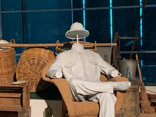 Mannequin of a Master Pearler, dressed in white, sitting on a wicker chair aboard a pearling lugger.