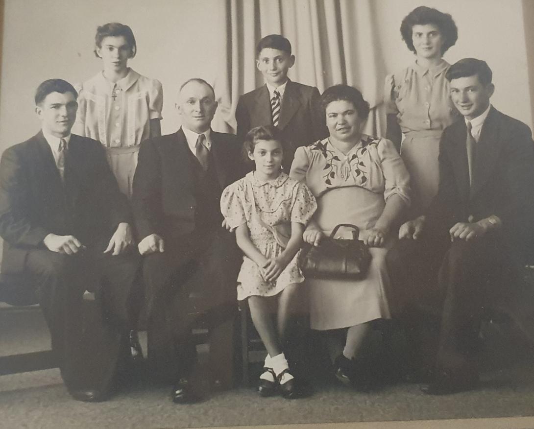 A black and white photo showing a family group of mother and father, three sons and three daughters. All are dressed nicely and arranged formally in a studio portrait.