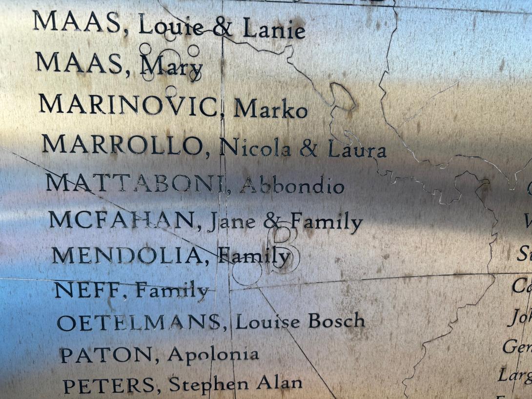 A close up of a silver panel inscribed with names.