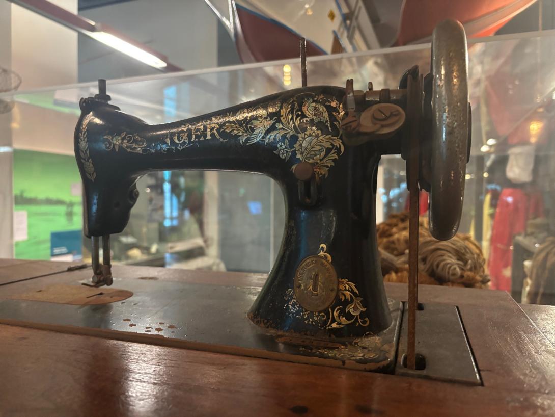 Vintage black Singer sewing machine with gold detailing, featuring a hand crank and mounted on a wooden base