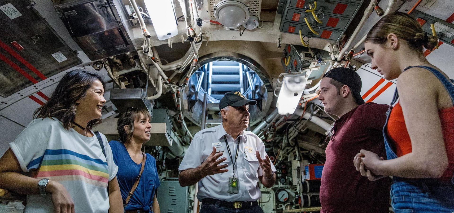One of our experienced volunteer tour guides leads a captivated tour group inside the submarine.