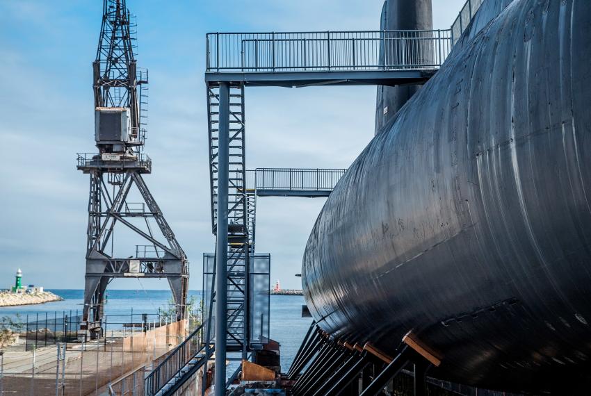 Looking down the long steel side of the submarine, we can see one of the old Harbour loading towers, and the harbour opening to the sea.