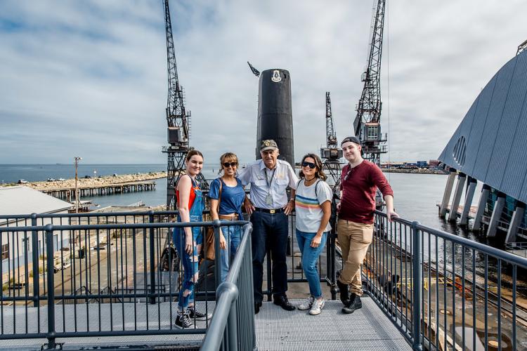 One of our experienced volunteer tour guides with a tour group on the walkway above the submarine.