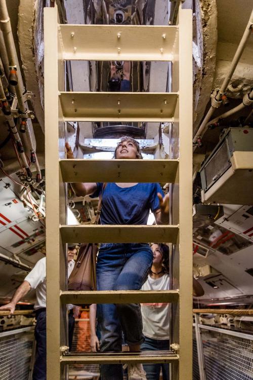 Submarine tour participants carefully use one of the metal ladders.