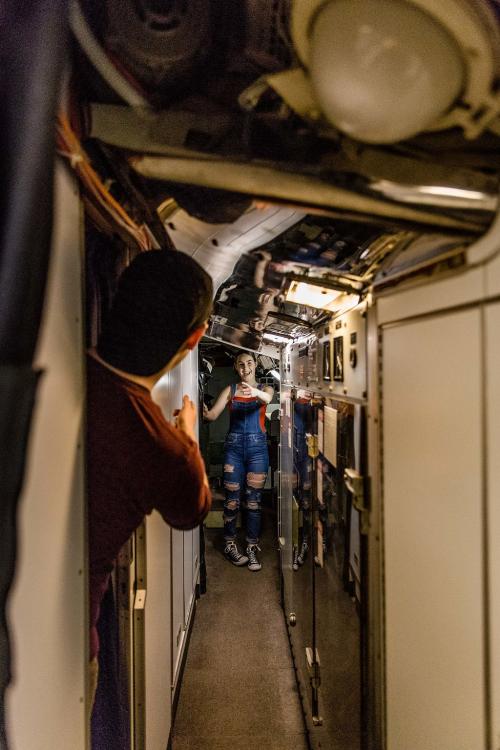 Two young tour participants happily greet one another from opposite ends of a narrow corridor.