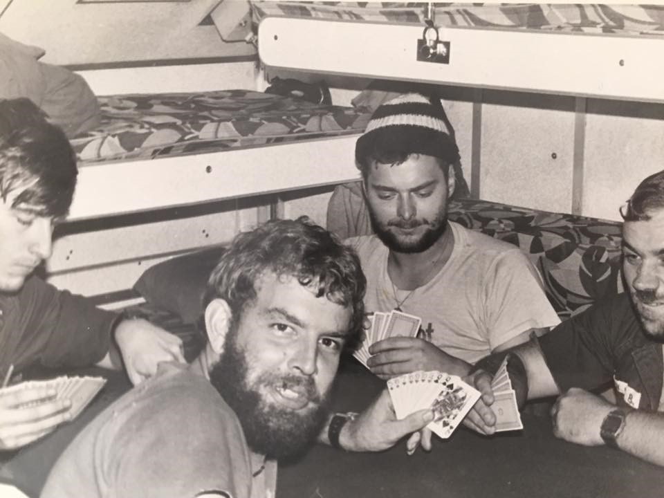 Four bearded submarine crew gathered around a table playing cards.
