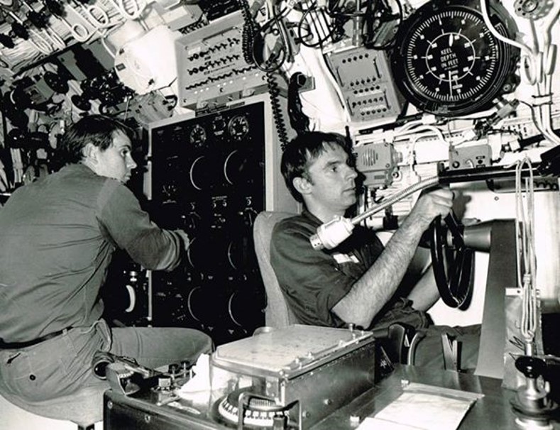 One crew is hunched over a large wall panel of dials while another sits tightly gripping the sub's steering wheel.