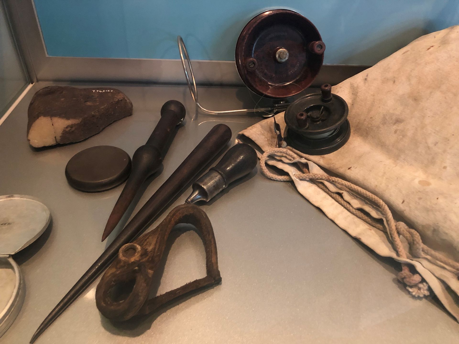 A collection of fishing reels and other equipment in a Museum display case.