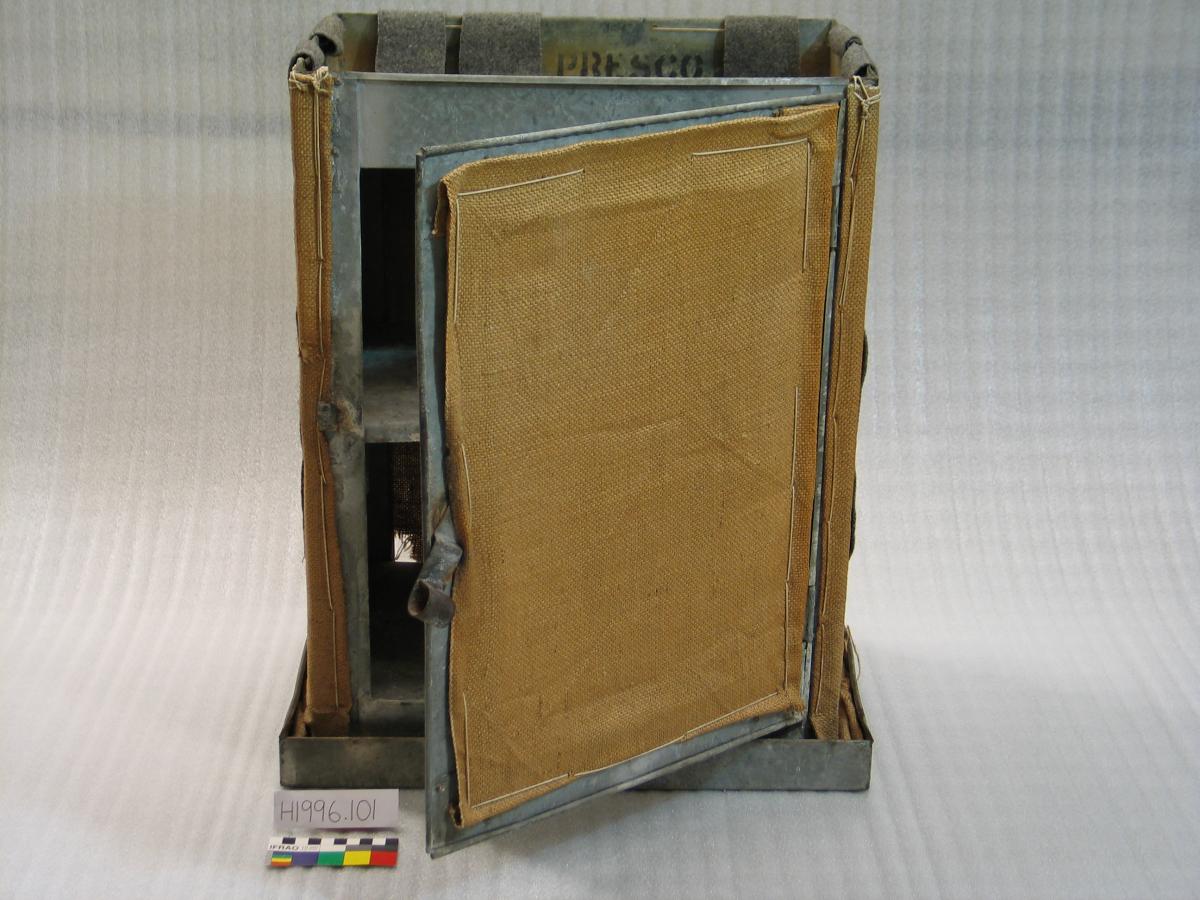 The safe has a metal rectangular tray at the bottom and a metal frame on top. The sides of the frame are covered with hessian material.