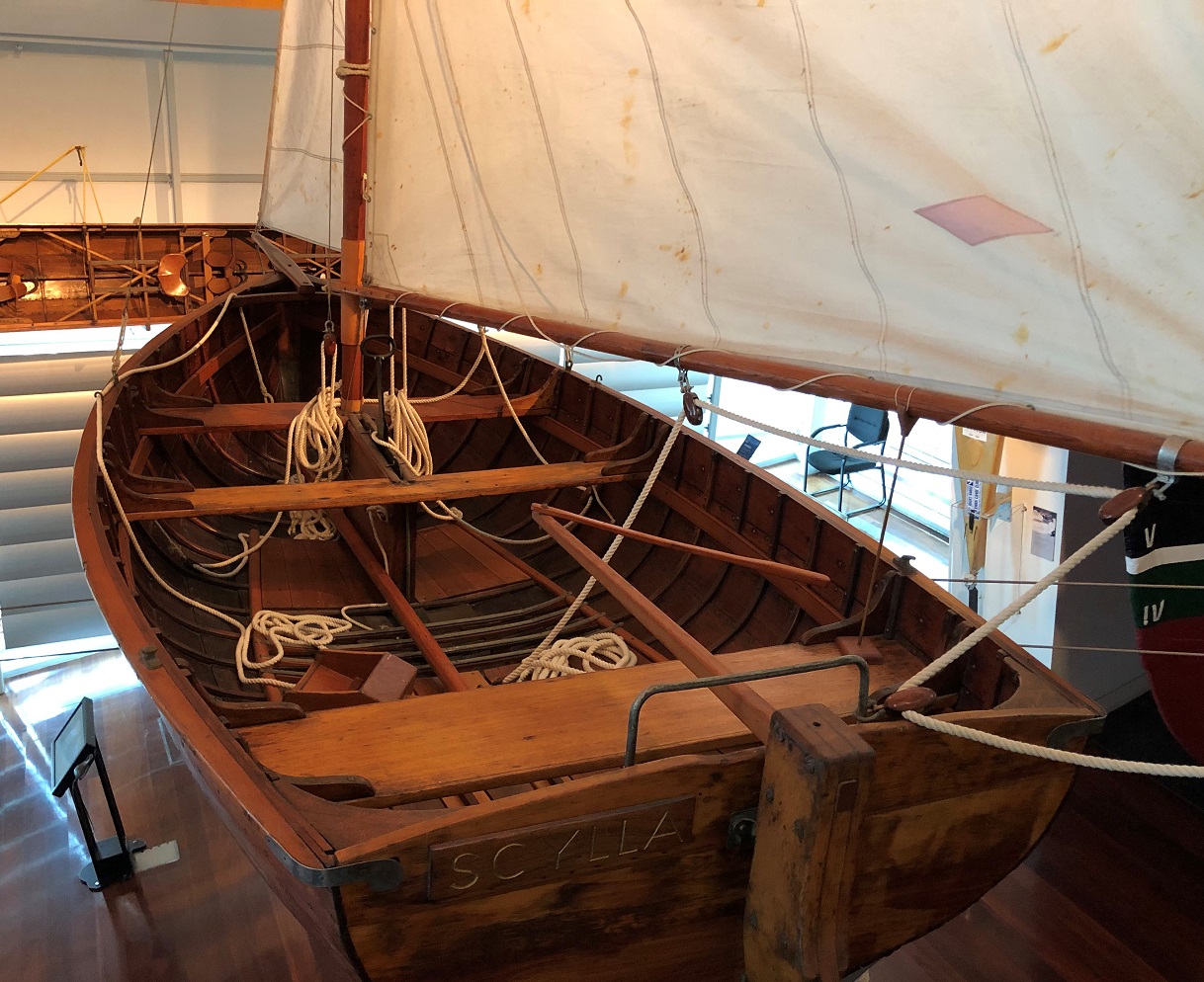 A wooden sailing boat suspended next to two others next to the walkway.
