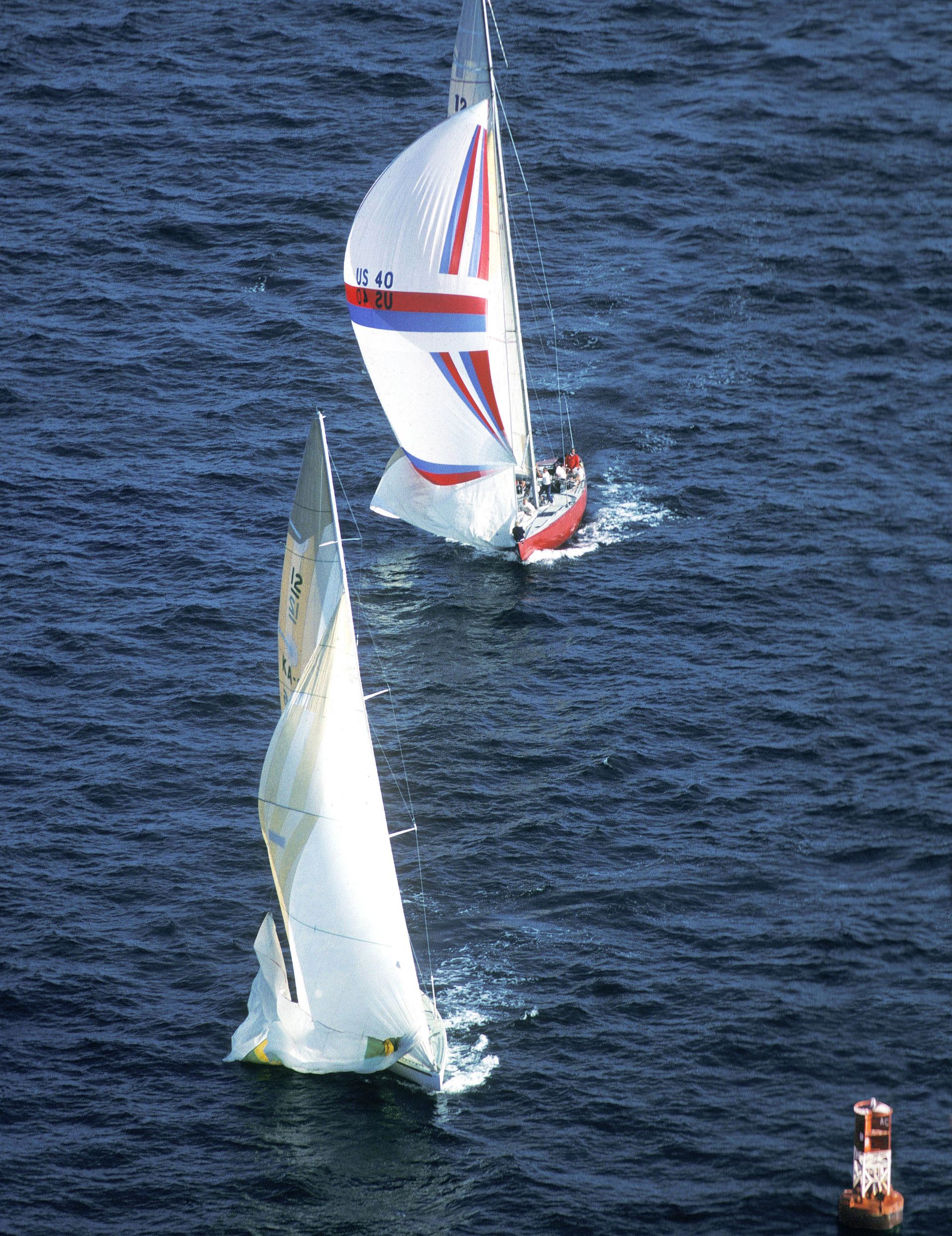 Australia II is about two boat lengths ahead of the other yacht as it approaches the orange buoy.