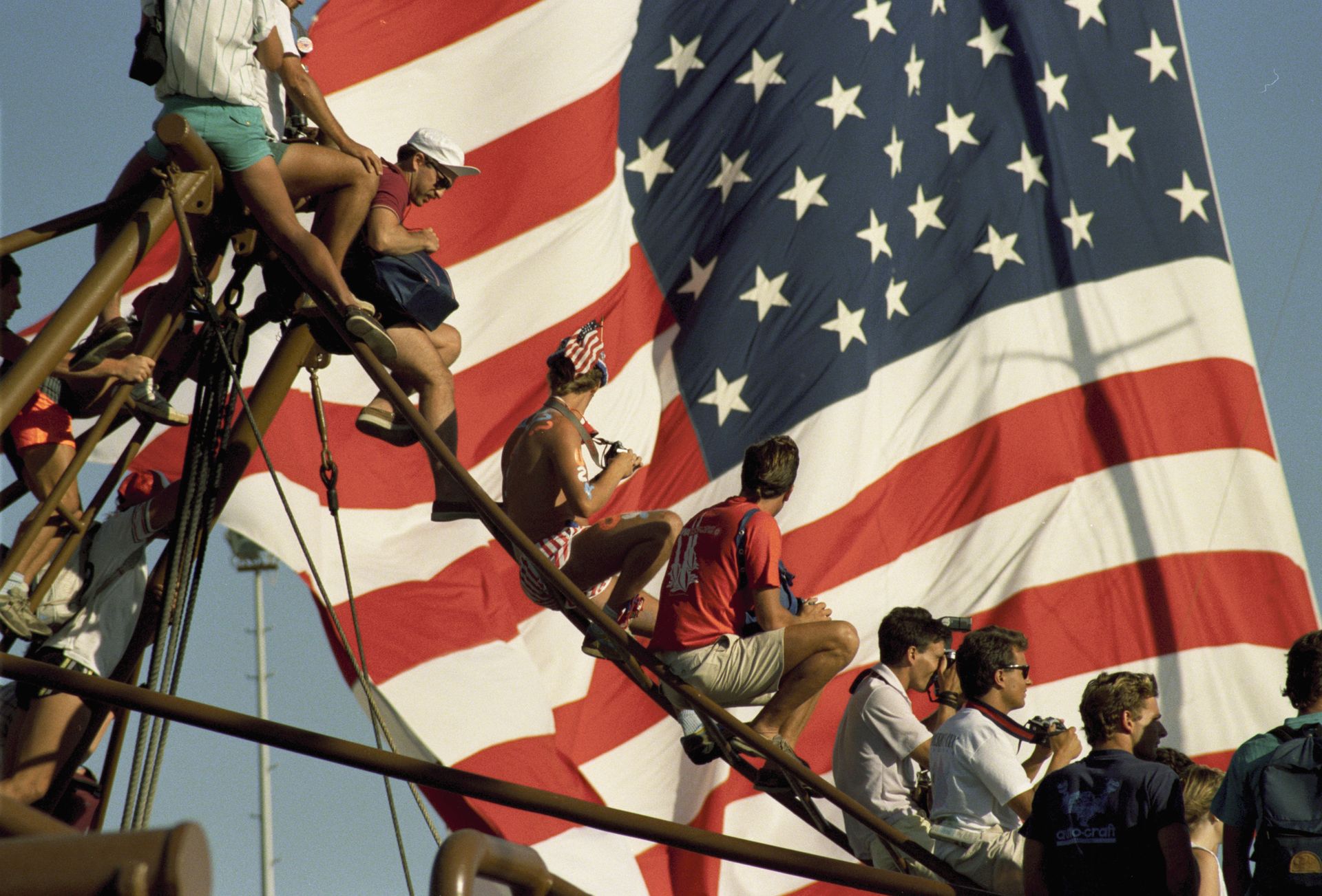 American tourists sitting on a boat with a giant United States flag in the background.