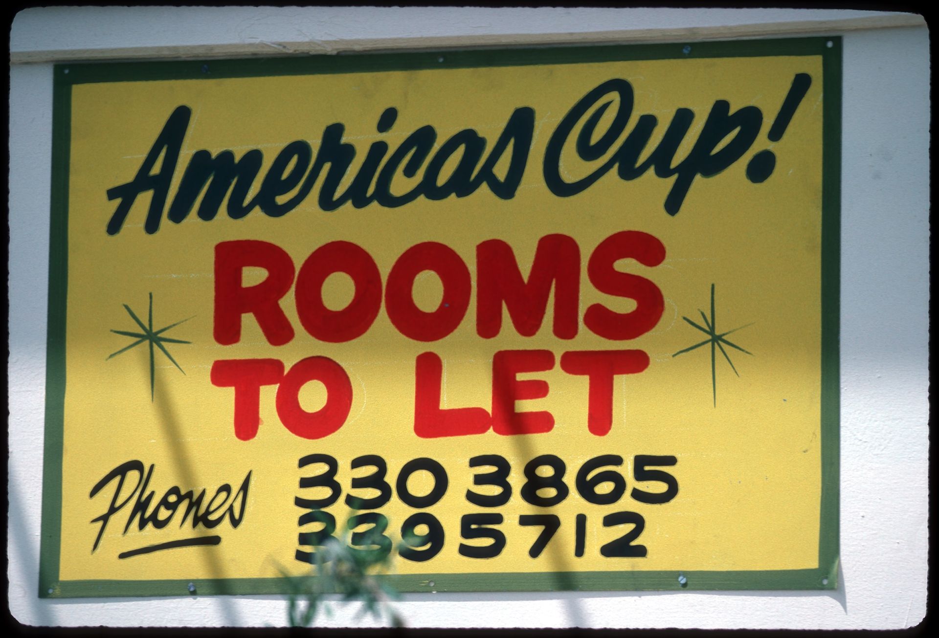 A sign reading "America's Cup! Rooms to let," followed" by two phone numbers with area codes 330 and 339.