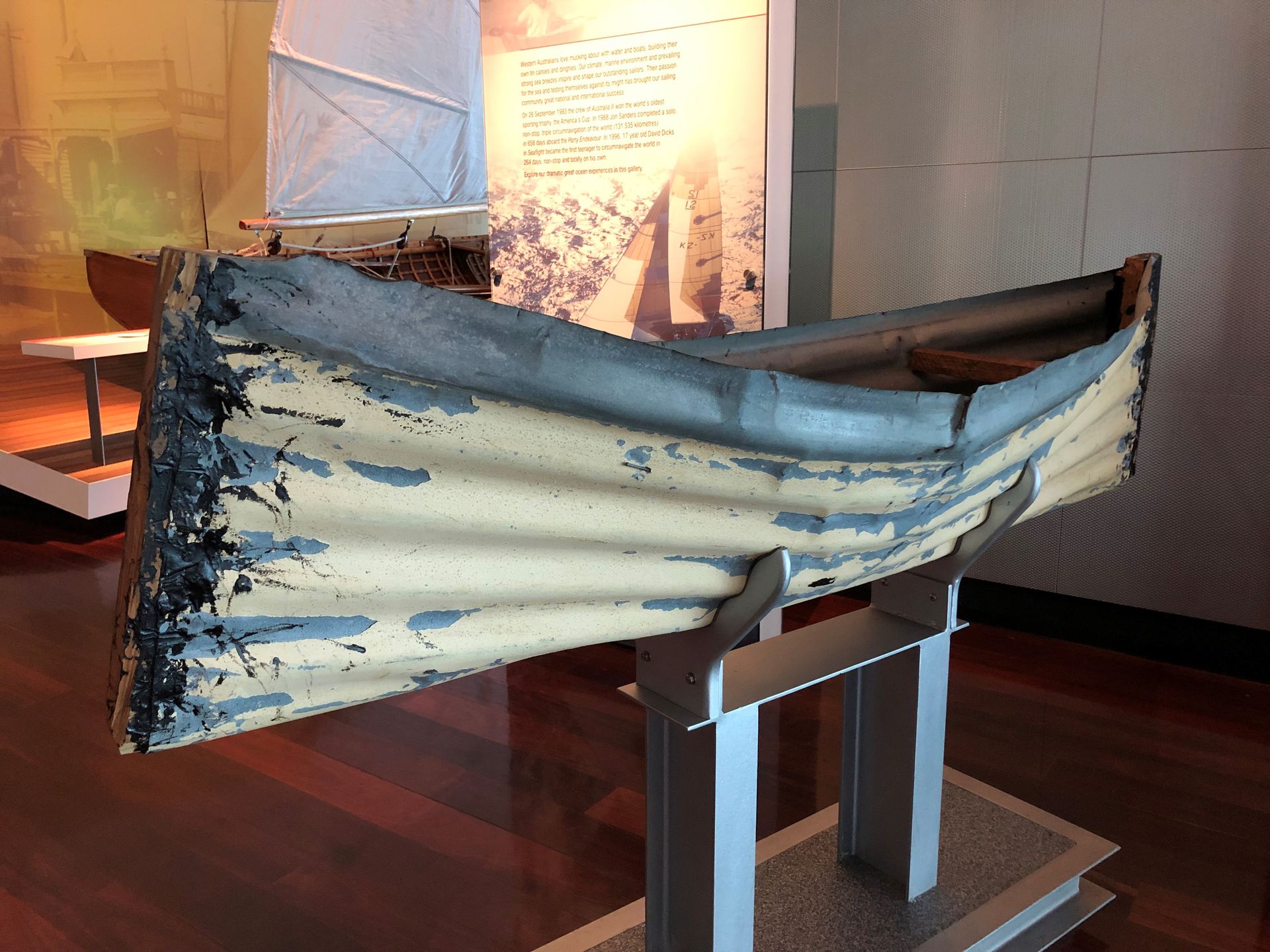 A small canoe made of tin is lifted about waist level off the floor of the Museum.