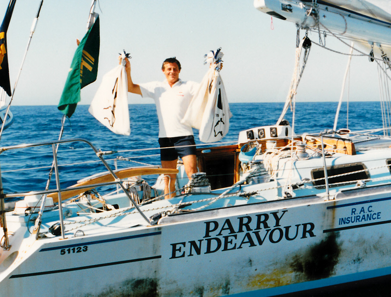 A grinning Jon Sanders holds up white sacks of mail on the deck of the yacht.