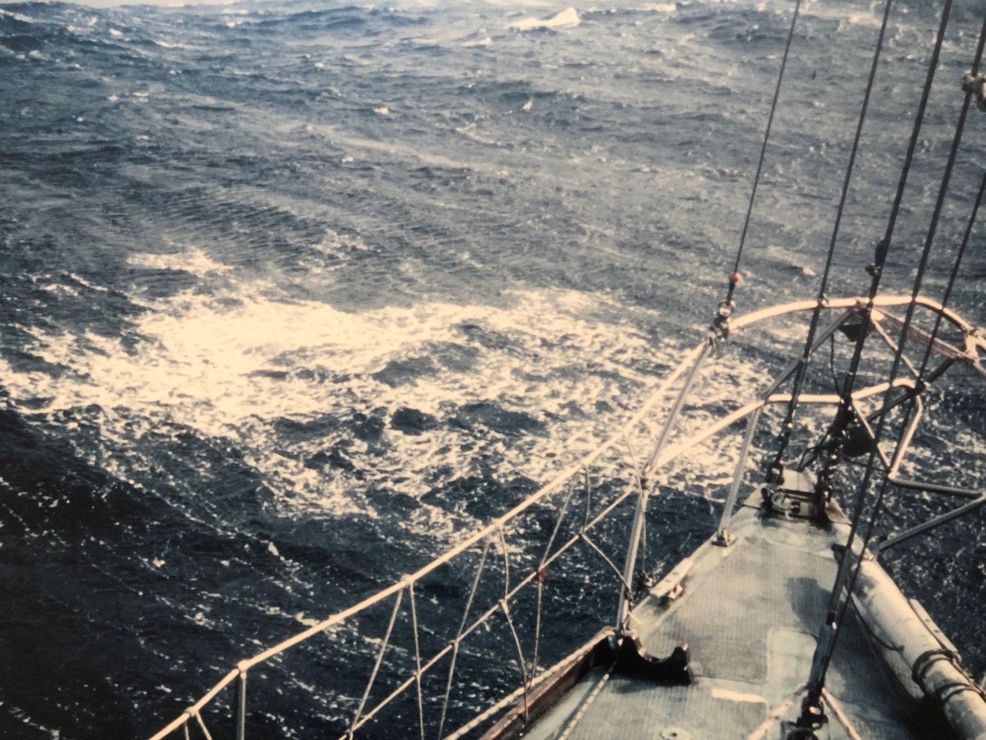 A photo taken from the front of the yacht shows the choppy sea beyond the metal railing.