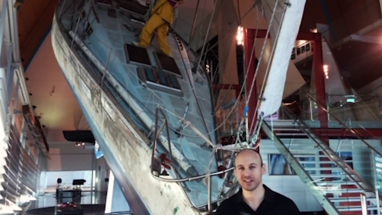 A friendly Museum staff member next to the dramatically leaning yacht in the gallery.