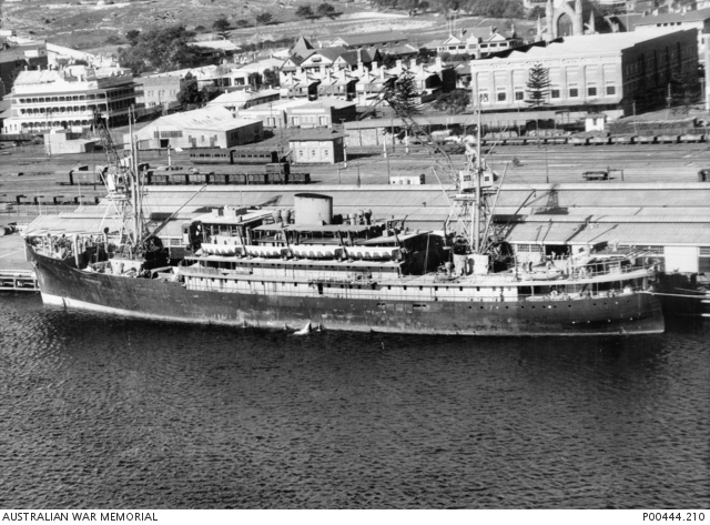 A large steam ship at harbour, Fremantle's old rail yards can be seen beside the dock.