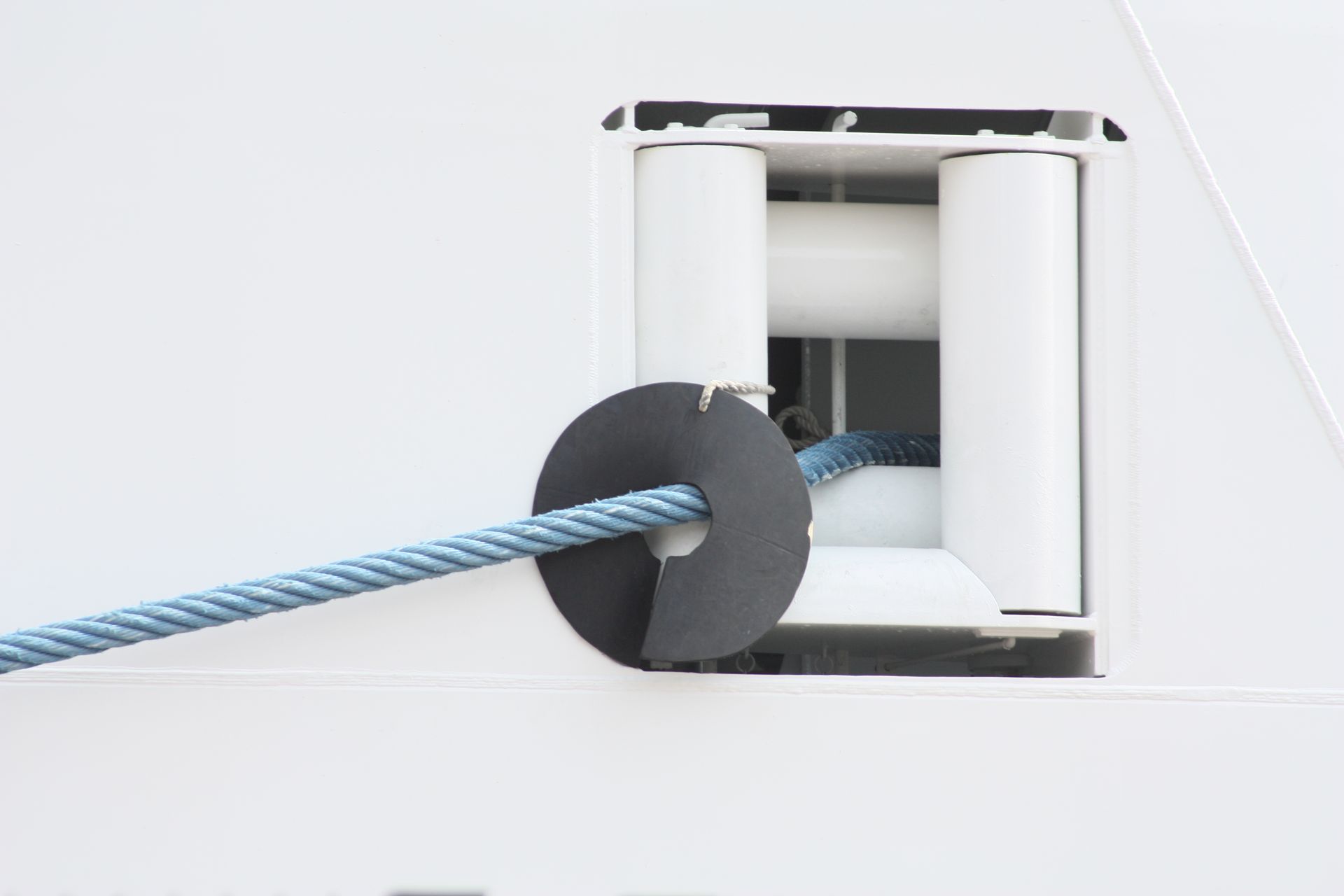 A large black disc around a strong blue rope emerging from the side of a ship.