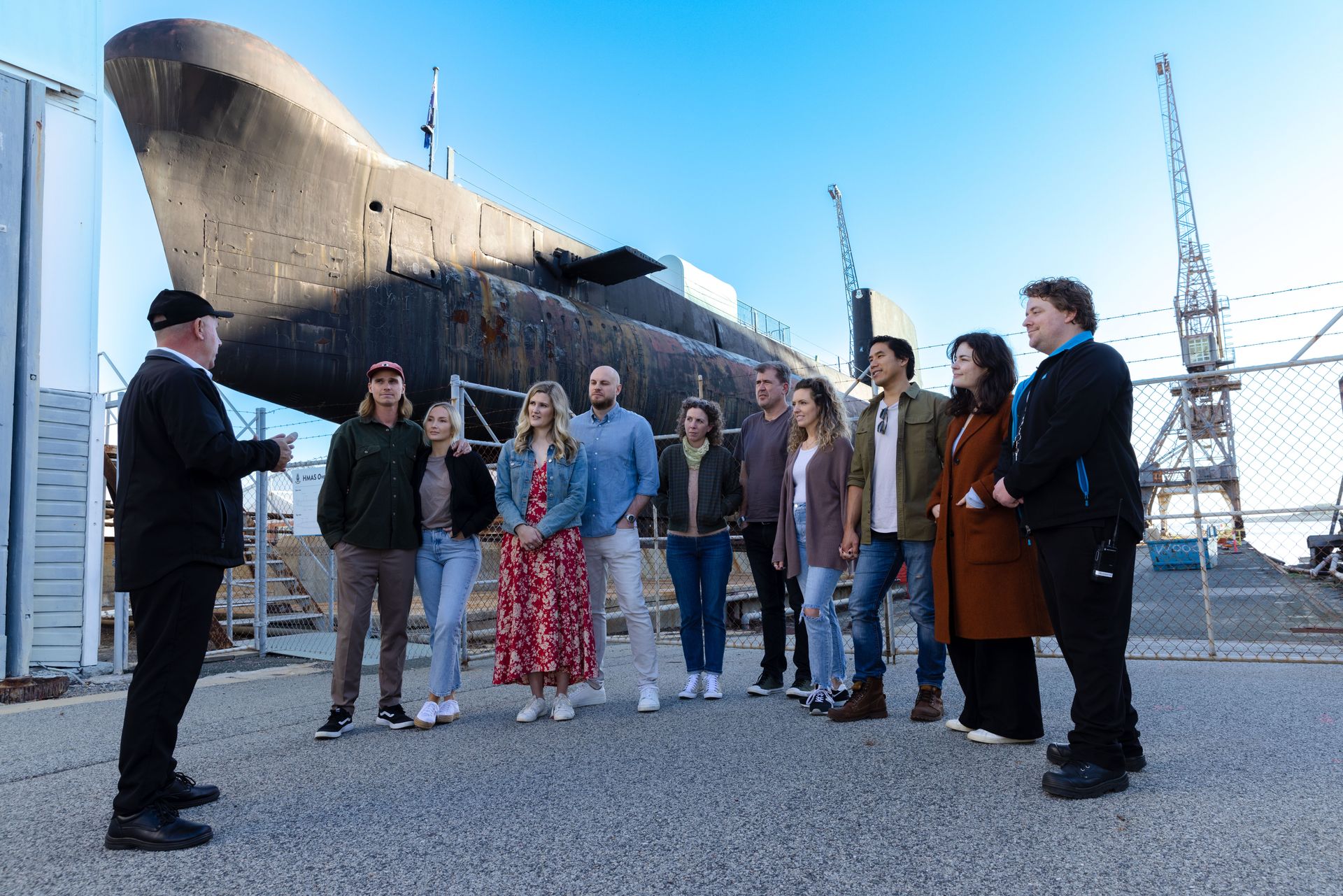 The Ovens submarine looms in the background as tour participants listen to the volunteer guide.
