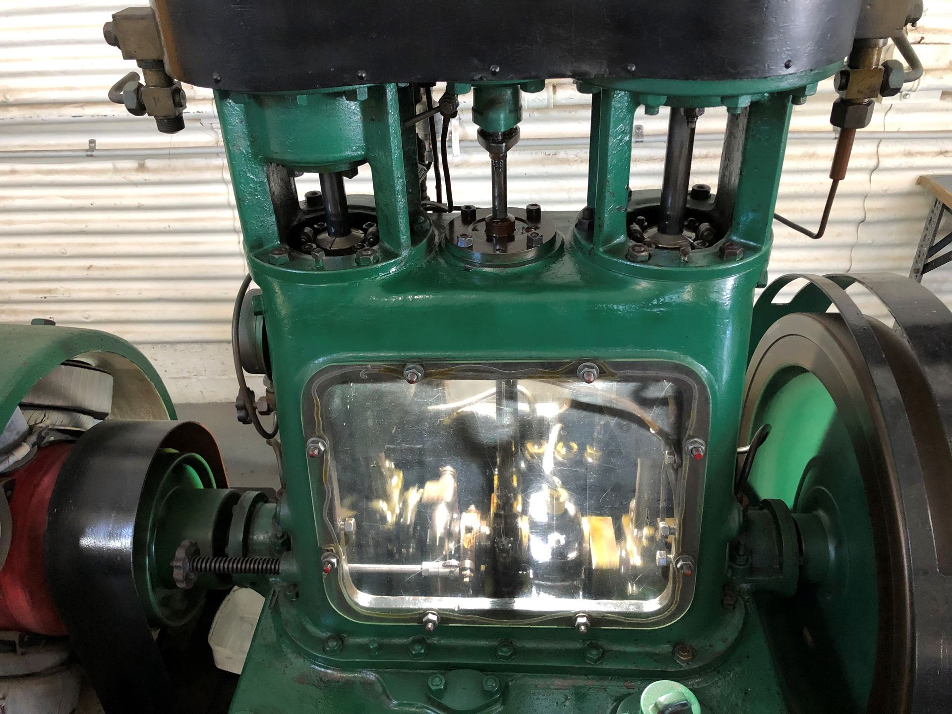 A large green engine mounted on the floor, a window in front showing the inner workings.