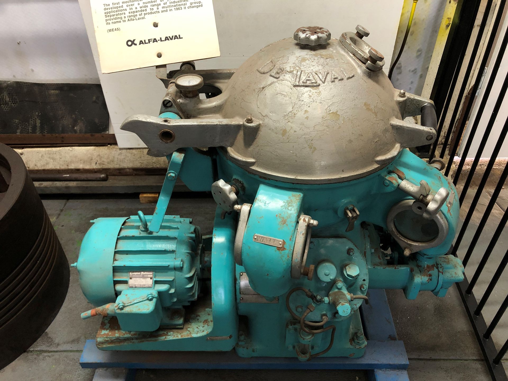 A pale blue motor with a grey dome on top mounted on the floor.