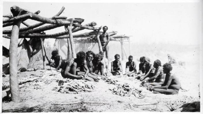 Aboriginal people sitting in a circle working on piles of trepang.