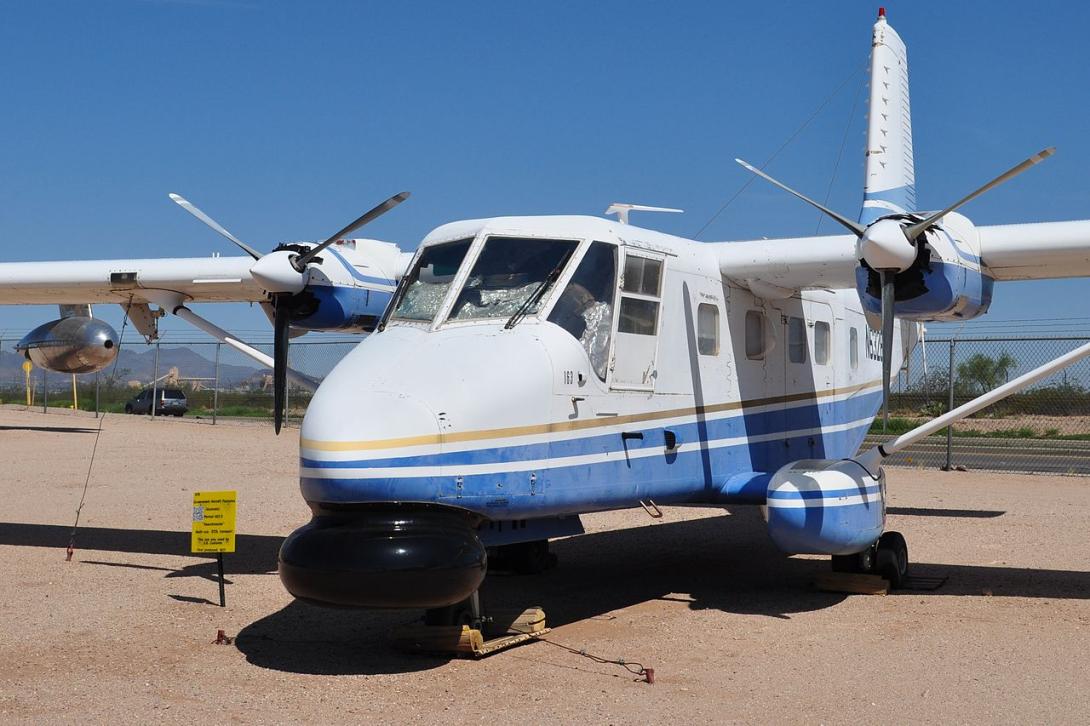 An aircraft on the ground with two propellers on its wings. A large black shape under its nose holds a sensor array.