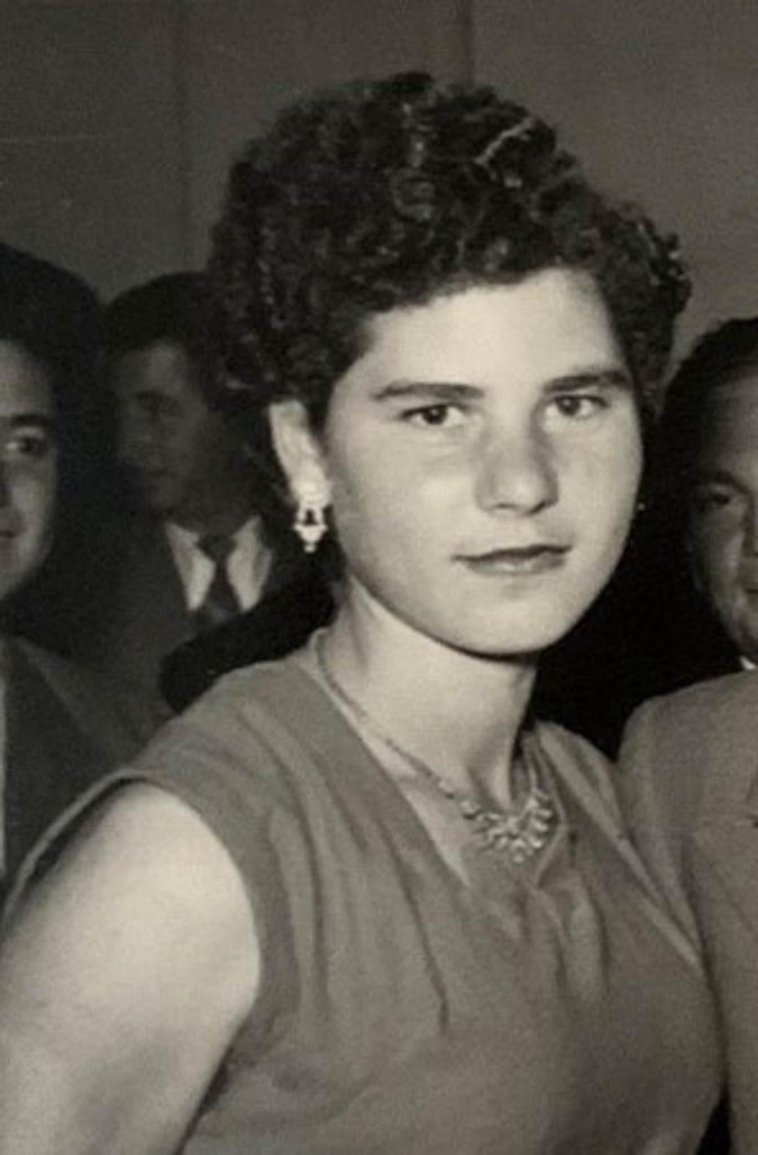 A young Lena in sleeveless dress in a crowd of people.