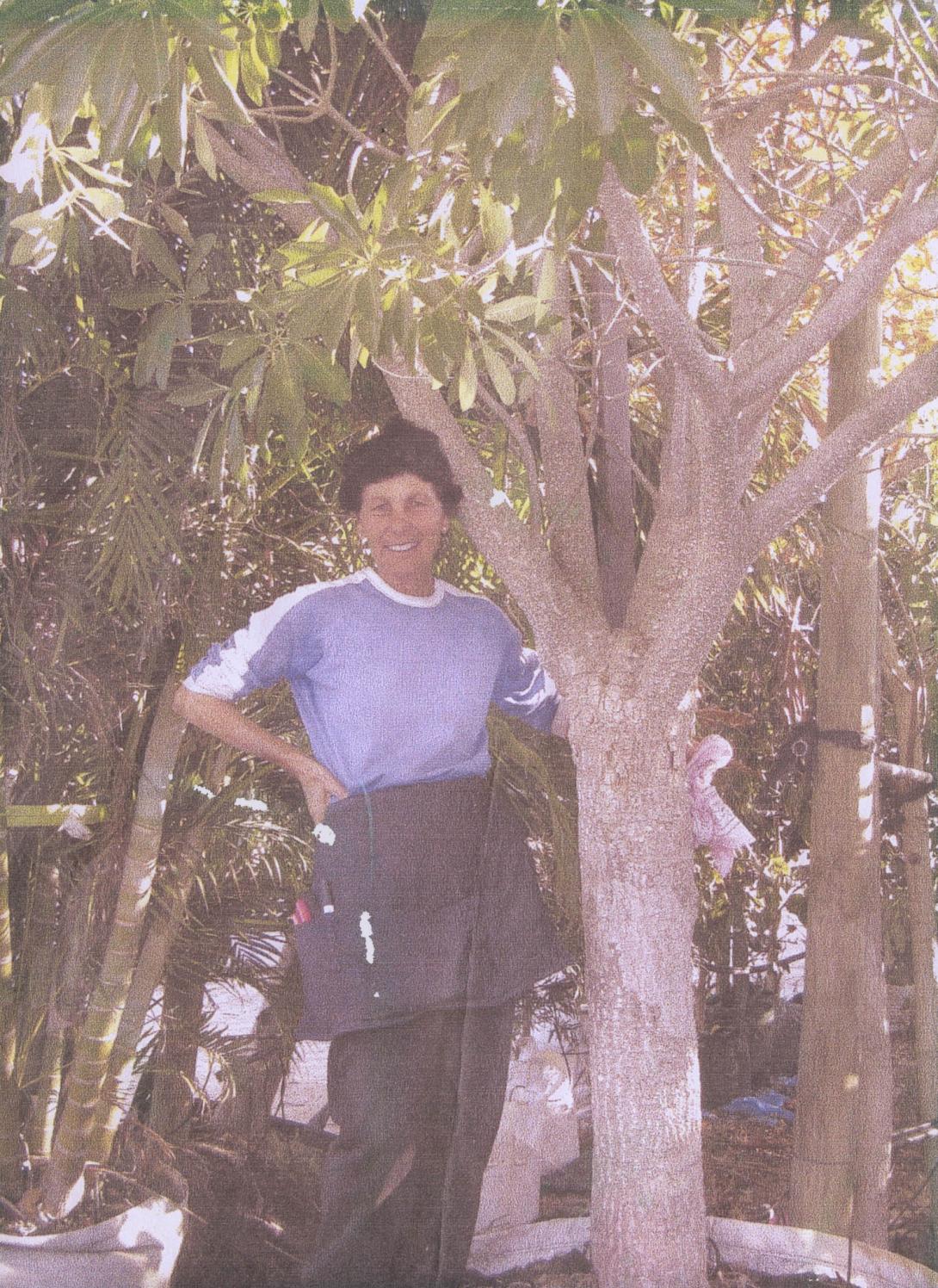 Lena in a work apron next to a tree.