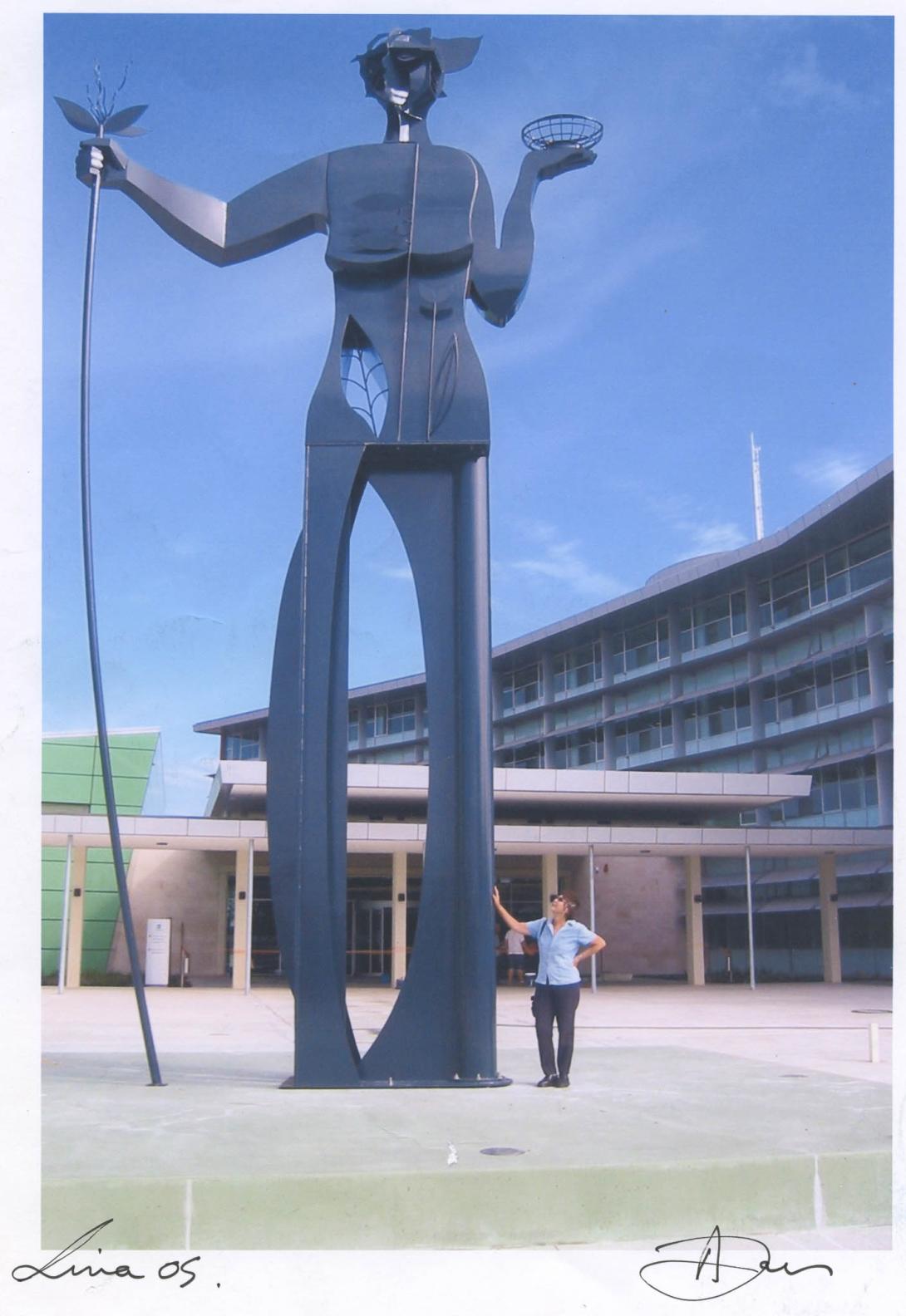 The statue of a human figure with a plant and pot dominates the photo.
