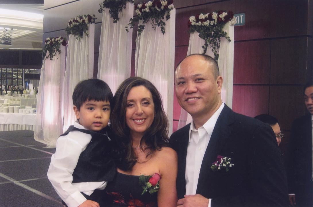 Tina and Stephen holding up a small boy for the camera at a fancy event.