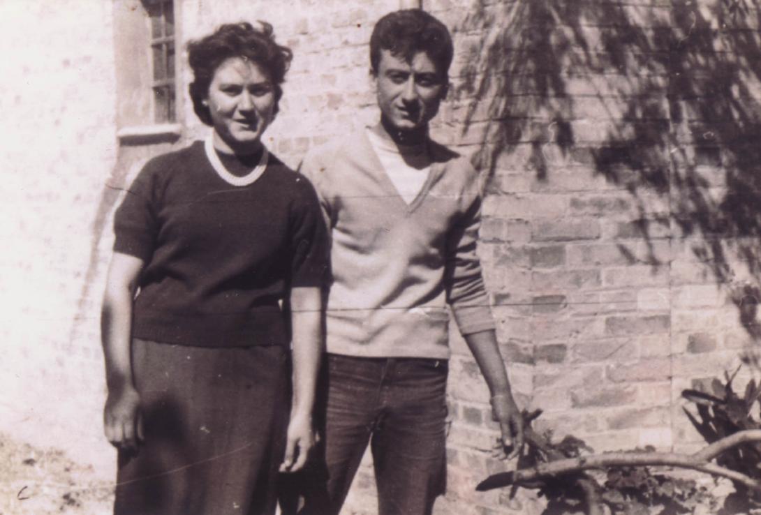 A young Giulia and Nick beside a brick building.