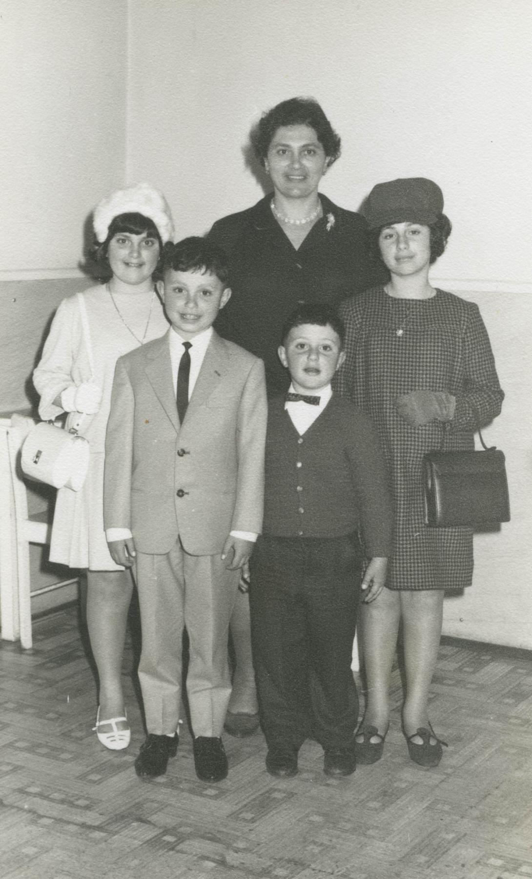 The family is well-dressed, the two boys in suits and a tie and bow-tie.