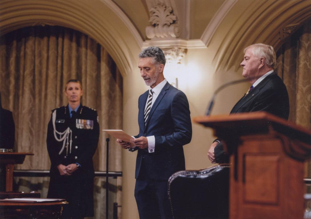 Tony reading a prepared statement beside a podium in an ornately architectured building.