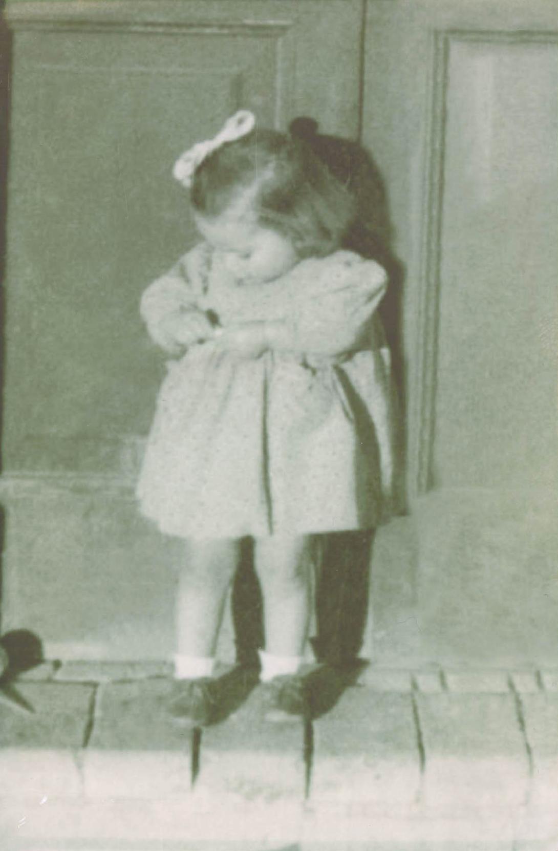 Anna as a toddler adjusting the waist of her pretty dress.