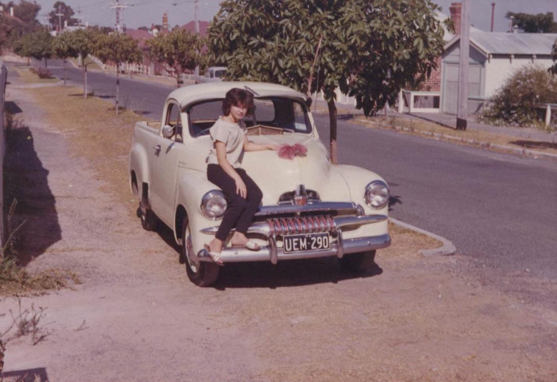 Anna has discarded the formal dresses of earlier photos for a t-shirt, pants and flip flops. She leans casually on the Holden ute.