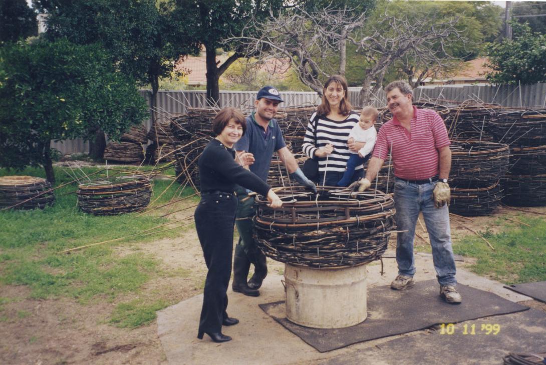 Many of the huge cane pots are stacked in the backyard. The family show off one that is resting on a tin drum.