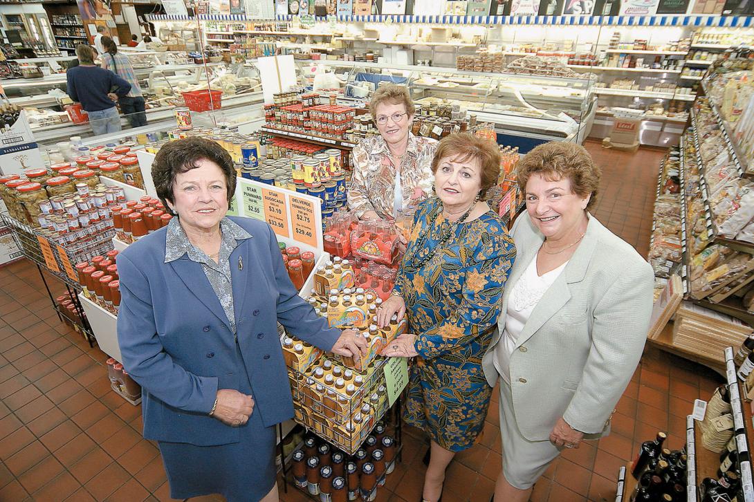 The sisters stand around many stacks of bottled sauces.