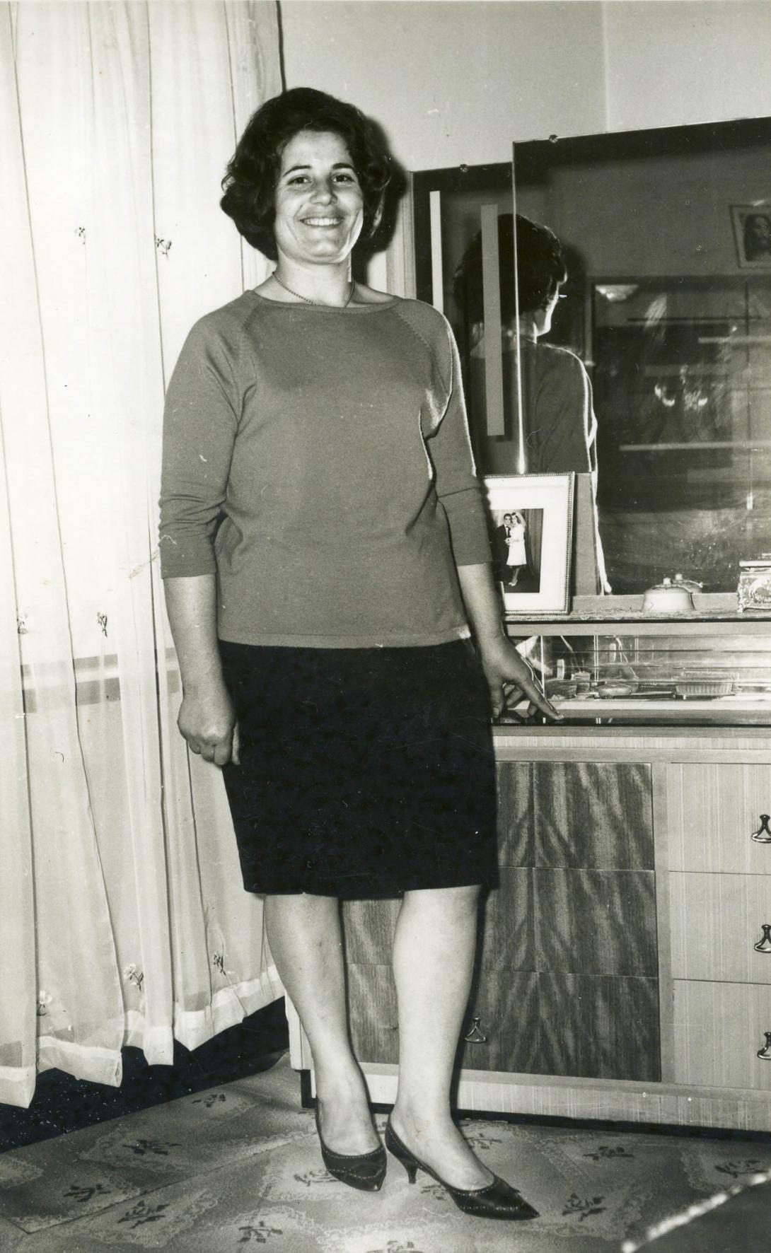 A smiling Adele standing in front of a cabinet.