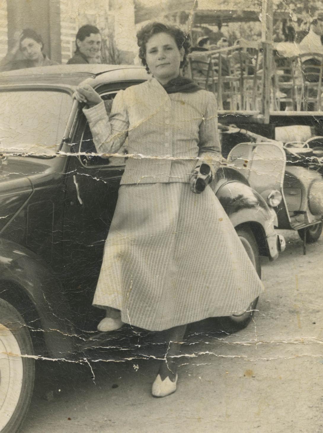 A young Adele at the side of a sleek dark-coloured car.