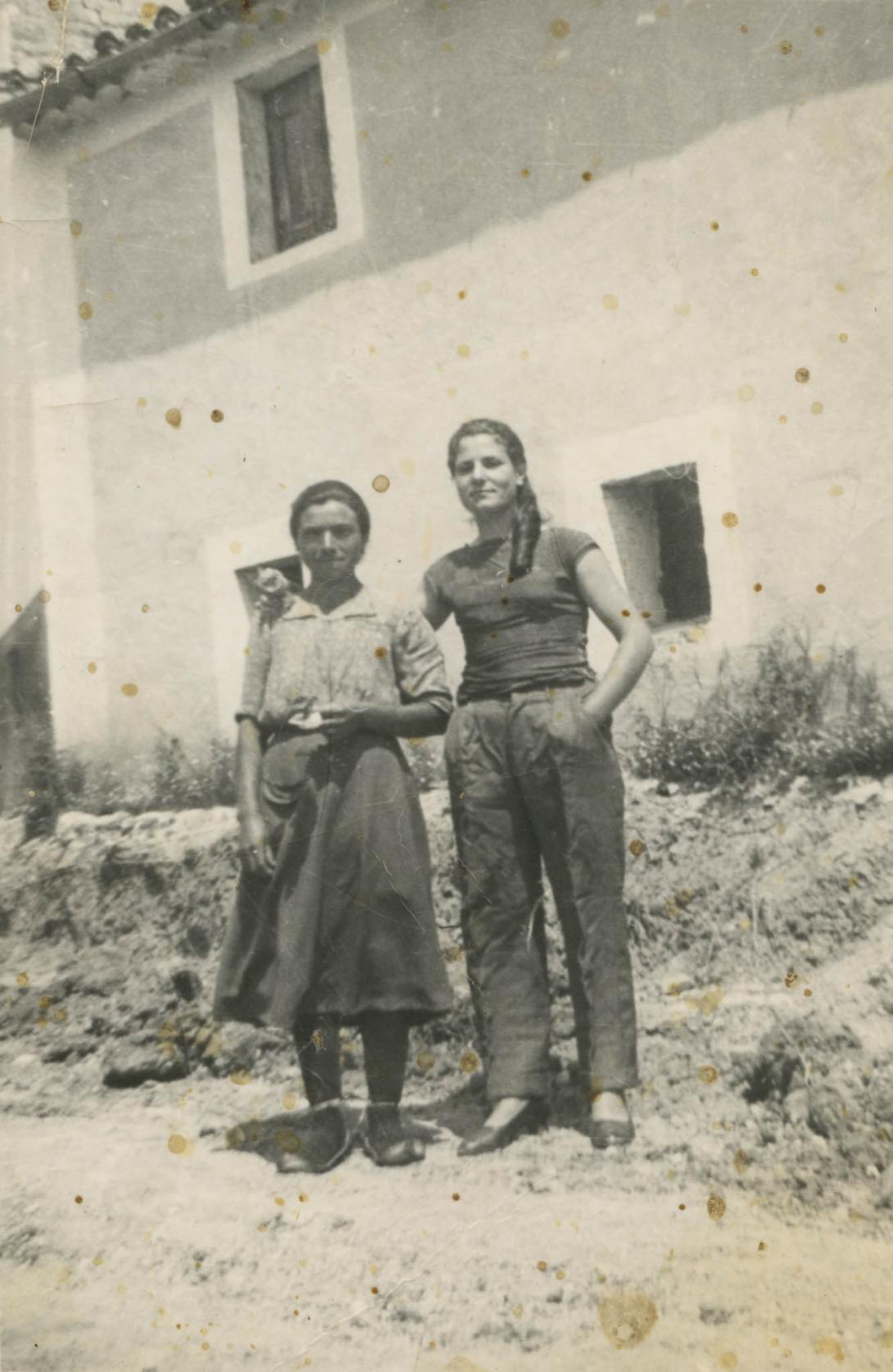 An old photo spotted with yellow stains showing Adele and her mother in front of a building.