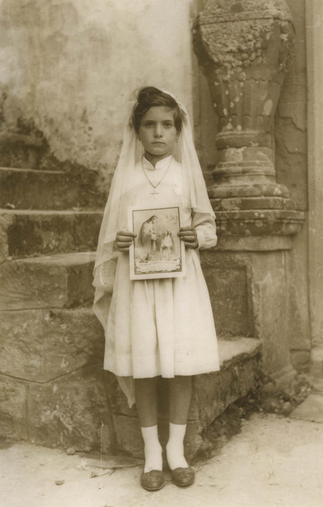 Vincenza in white dress and veil, holding a picture of Jesus giving Communion.