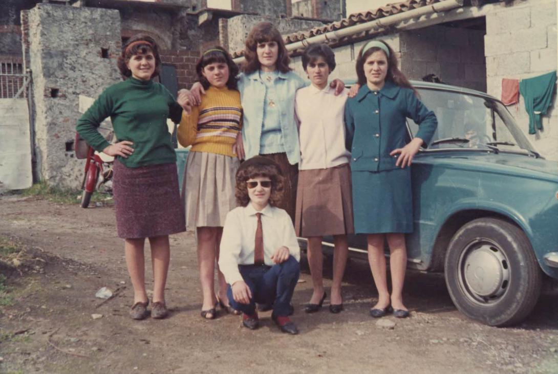 The family in colourful clothing in front of a shiny old car.