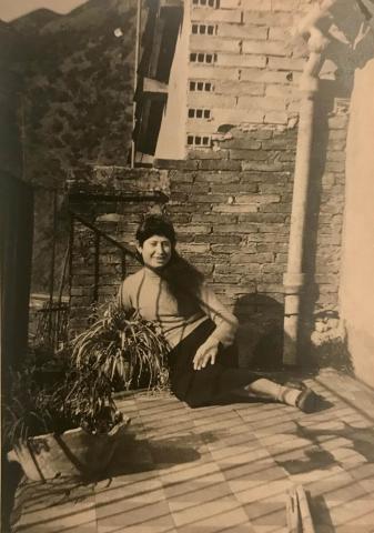 Yellowed photo of a girl in front of a crumbling brick wall.